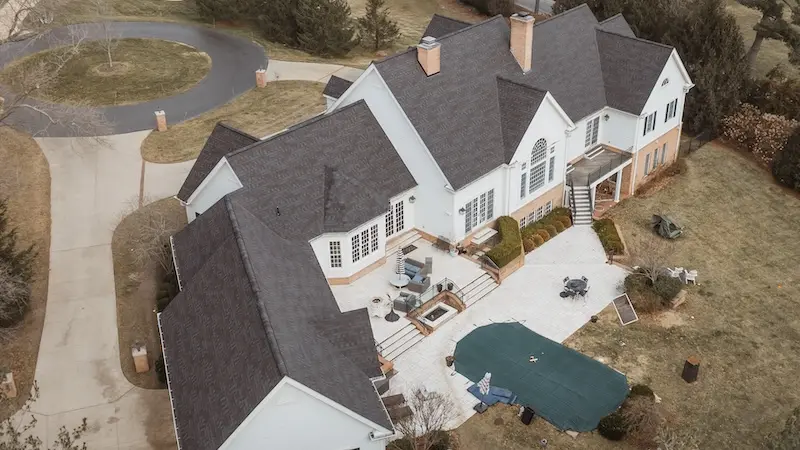 Aerial drone view of luxury white estate with insurance claim roof replacement completed by Cardinal Contractors serving Kansas City and St. Louis Missouri