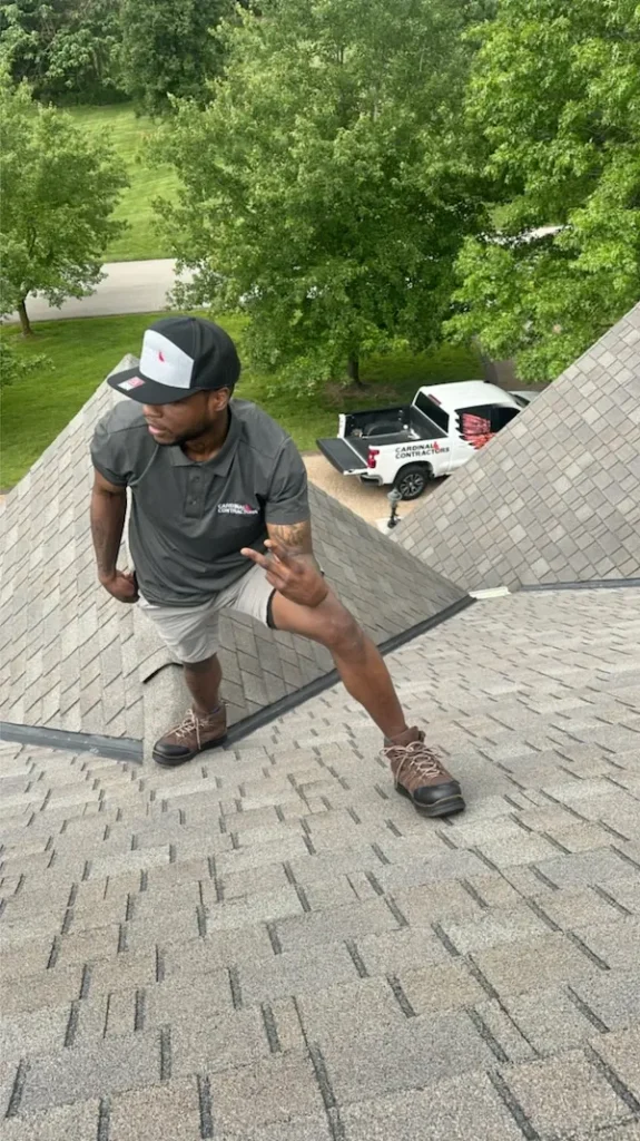 Cardinal Contractors crew member inspecting shingles on residential roof in St. Louis MO to assess need for roof replacement