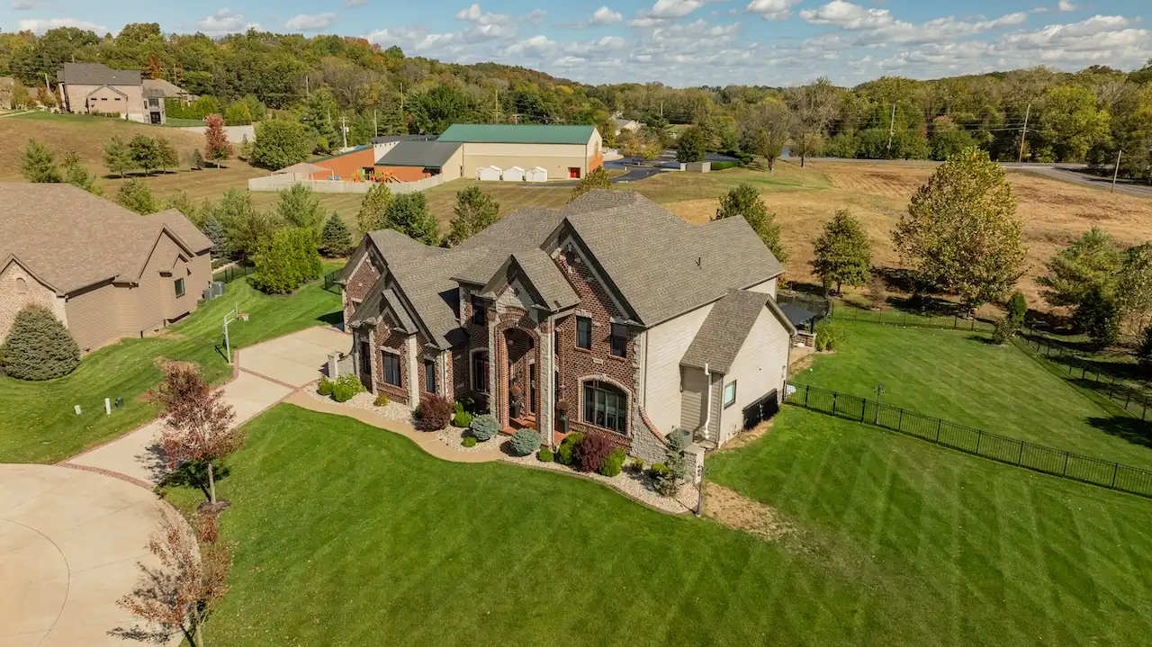 Aerial drone view of luxury dark brick estate with completed roof replacement by Cardinal Contractors in Leawood KS