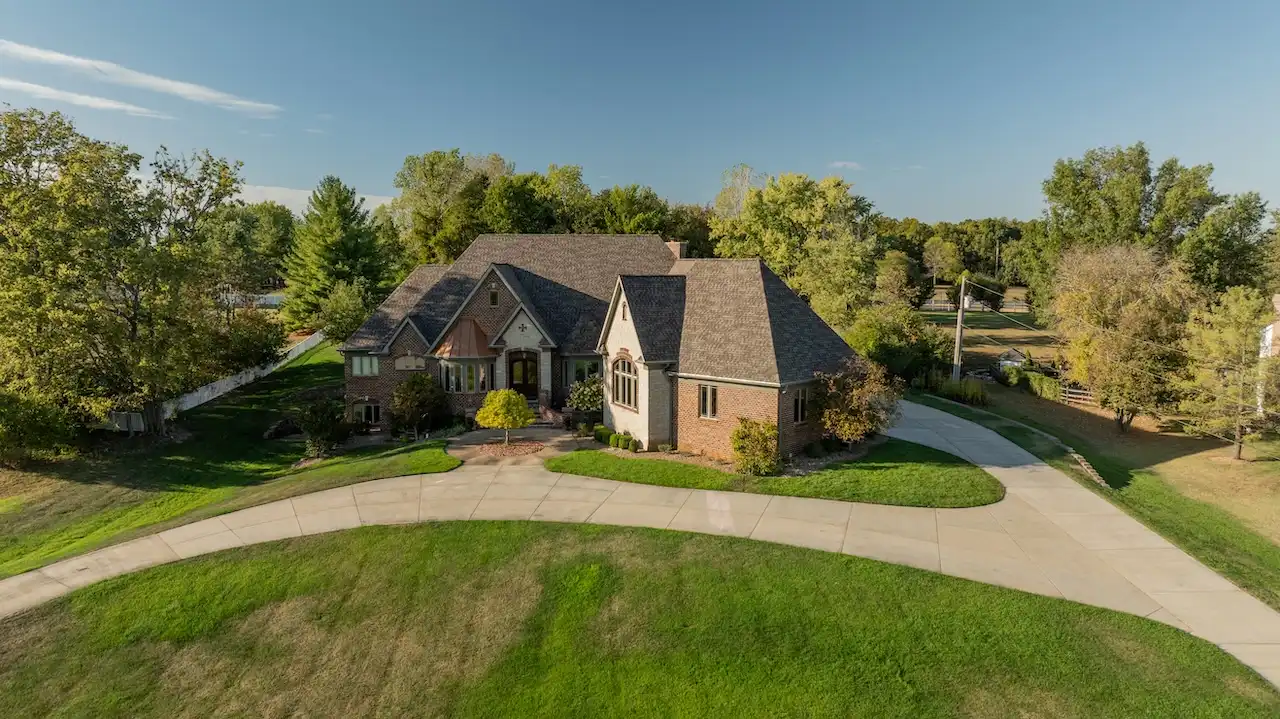 Aerial drone view of luxury Tudor style home with completed roof replacement by Cardinal Contractors in Lenexa KS