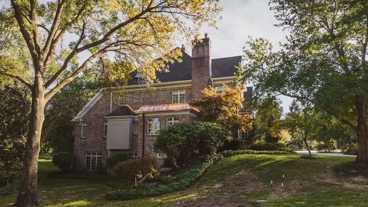 Ground level view of historic brick manor with dark roof replacement and copper accent detail completed by Cardinal Contractors serving Kansas City and St. Louis Missouri