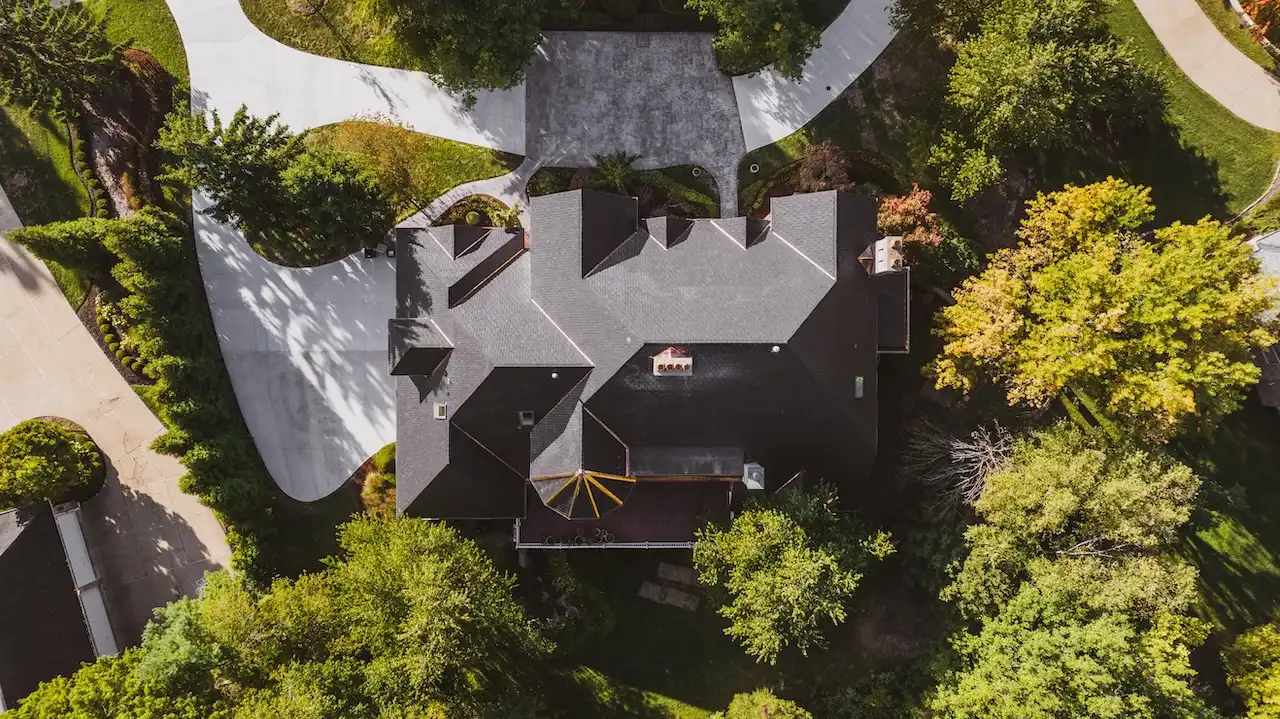 Overhead drone view of luxury estate with dark multi-pitch roof replacement and circular driveway completed by Cardinal Contractors serving Kansas City and St. Louis Missouri
