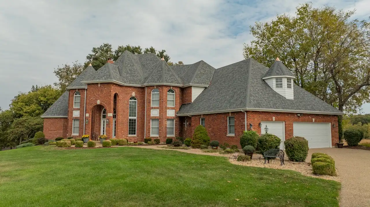 Luxury brick French chateau style home with completed roof replacement by Cardinal Contractors in Olathe KS