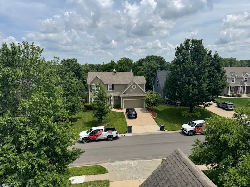 Cardinal Contractors branded trucks and crew on rooftop during storm damage insurance claim roof replacement in St. Louis MO