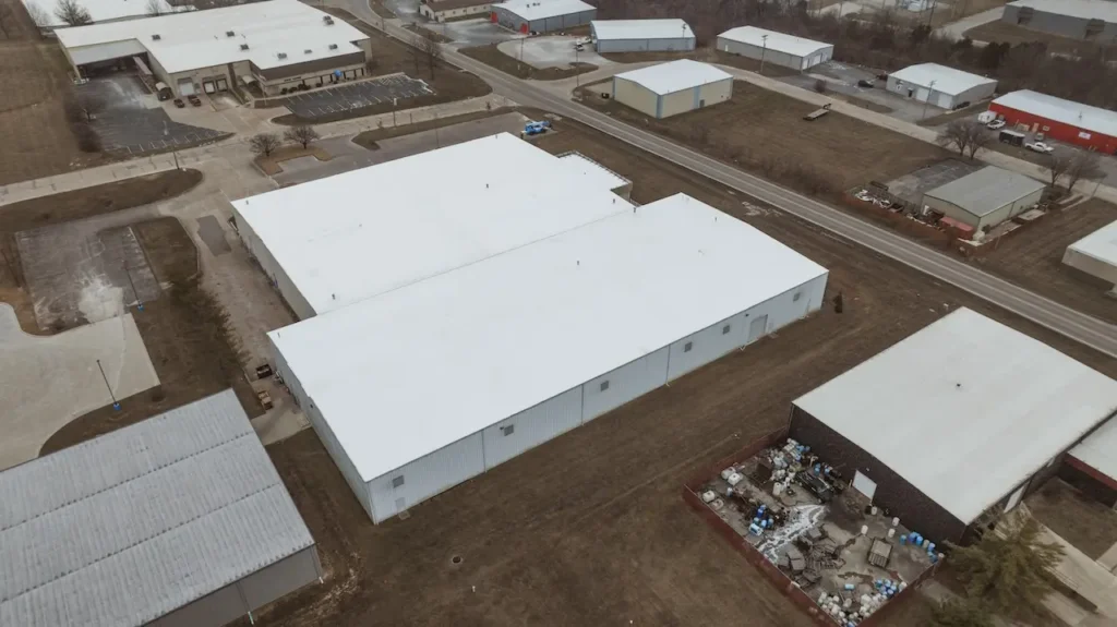 Aerial drone view of large industrial warehouse with completed commercial flat roof installation by Cardinal Contractors serving St. Louis MO commercial roofing