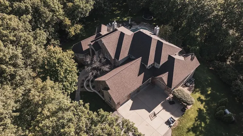 Aerial drone view of luxury estate with warm brown roof replacement completed by Cardinal Contractors for insurance claim roofing in St. Louis MO